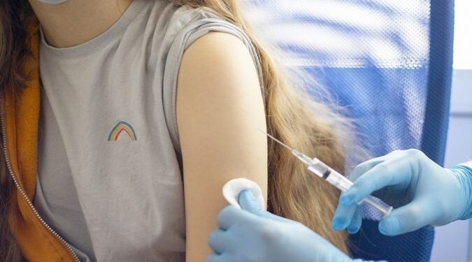 a doctor in gloves vaccinates a teenage girl
